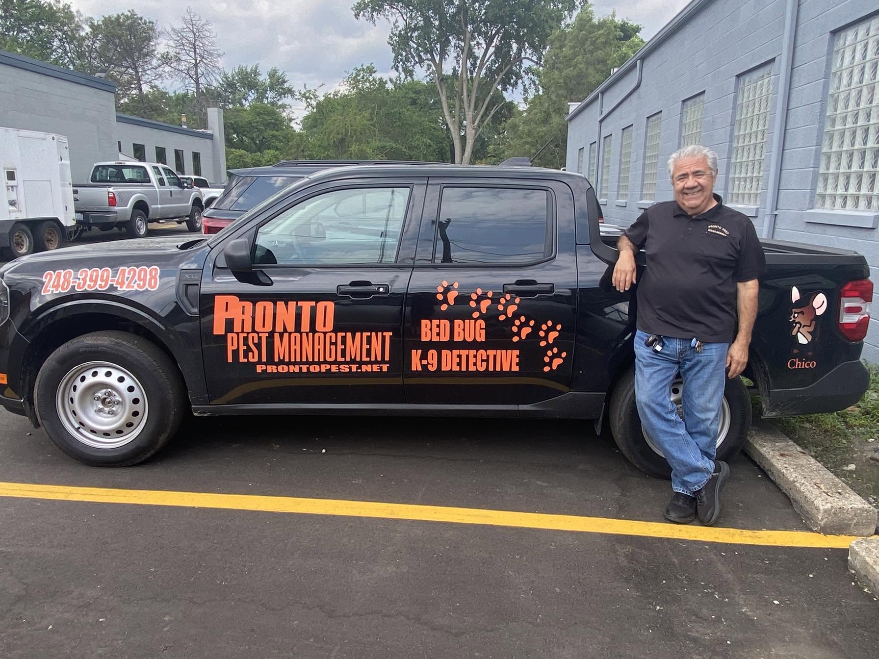 A man stands beside a car showcasing a vibrant and artistic paint job that has name on the company.