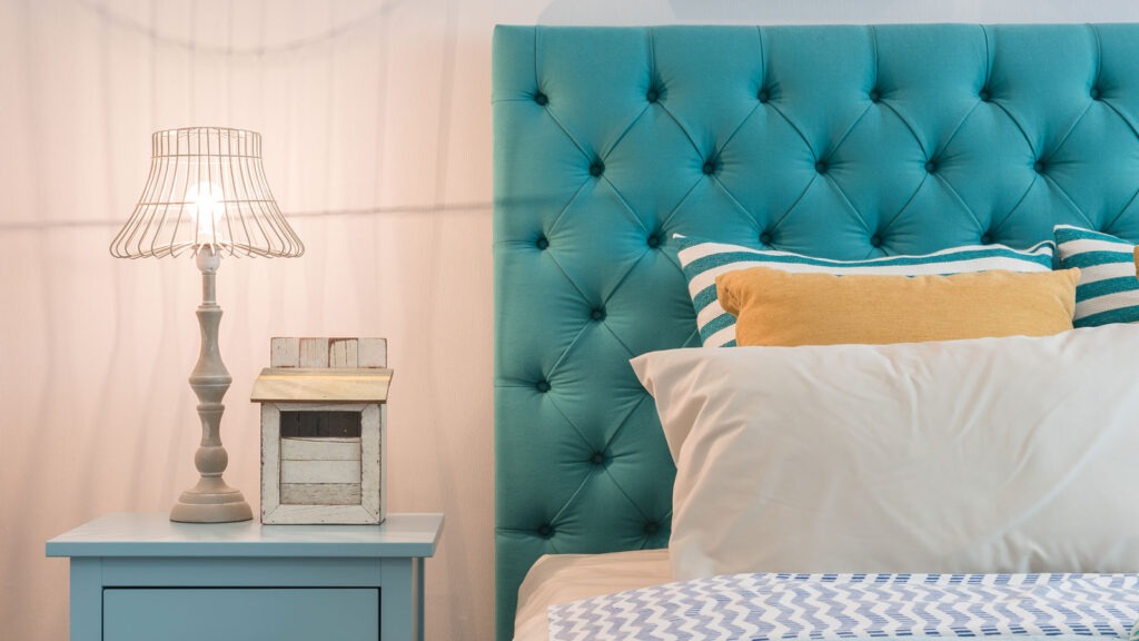 A bed featuring a blue headboard, neatly made with white bedding and decorative pillows.