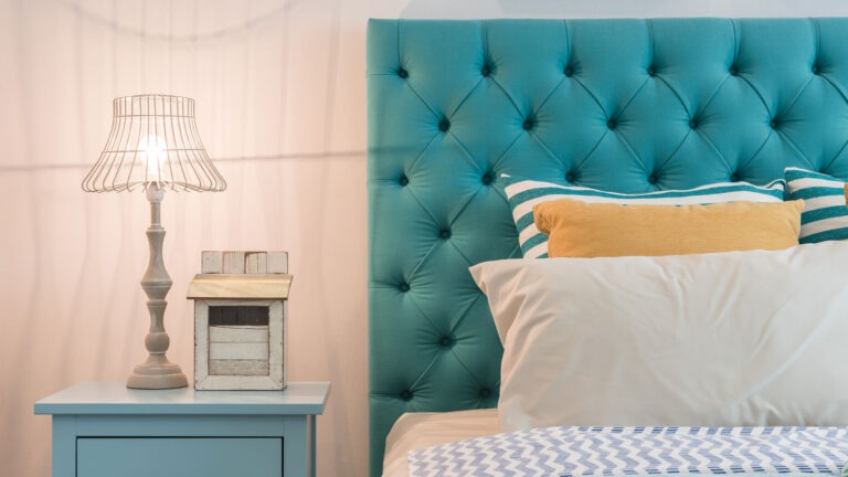 A bed featuring a blue headboard, neatly made with white bedding and decorative pillows.
